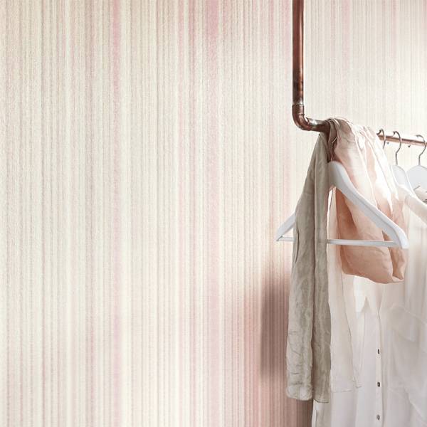 Raumdetail mit Kleiderstange und Kleiderbügeln vor Streifentapete in rosa von Guido Maria Kretschmer bei Heineking24